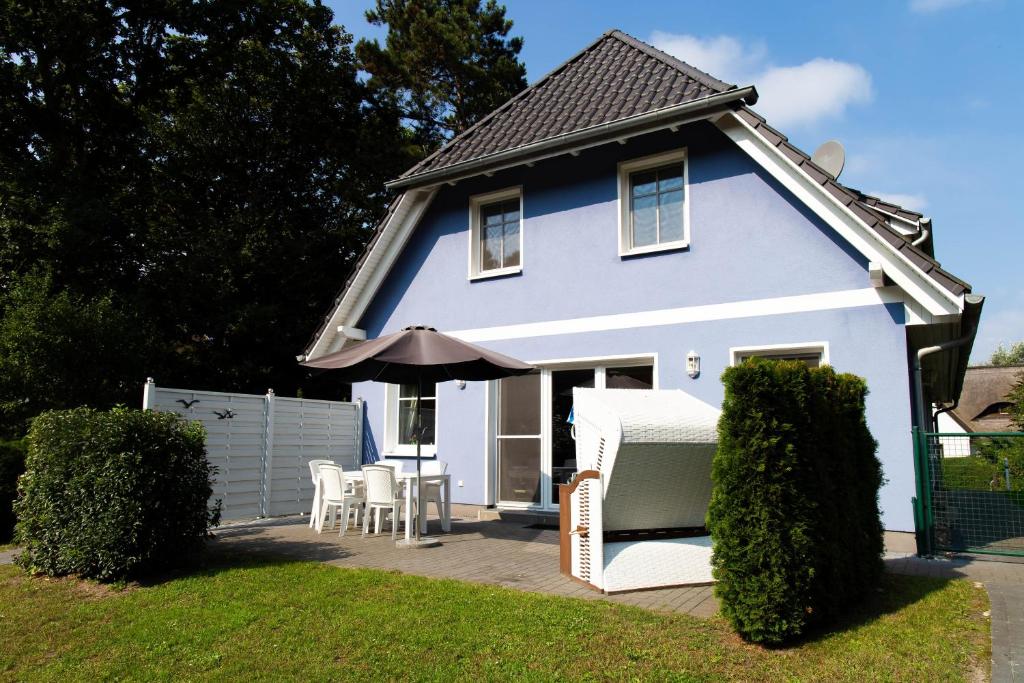 a blue house with chairs and an umbrella at Strandhaus Gabriella 02 in Ahrenshoop
