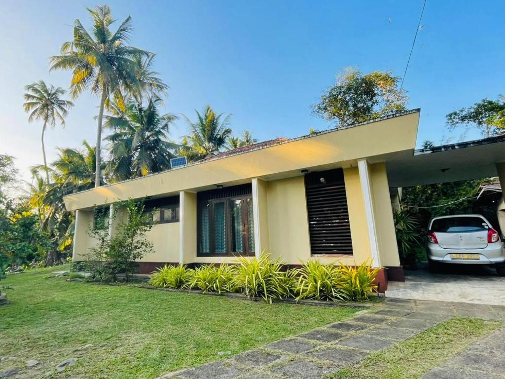 a house with a car parked in front of it at Serene Garden Lodge in Ahangama