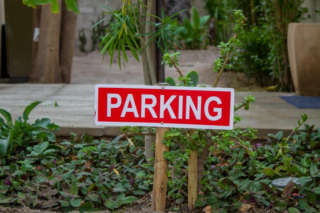 a red and white parking sign in a garden at Moxwini Self Catering Apartments in Maun