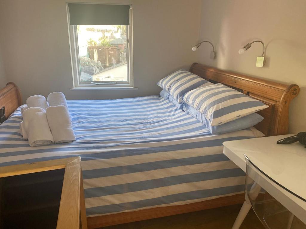 a bed with two pillows on it with a window at Crows Nest - cosy, tiny cottage in Castletown