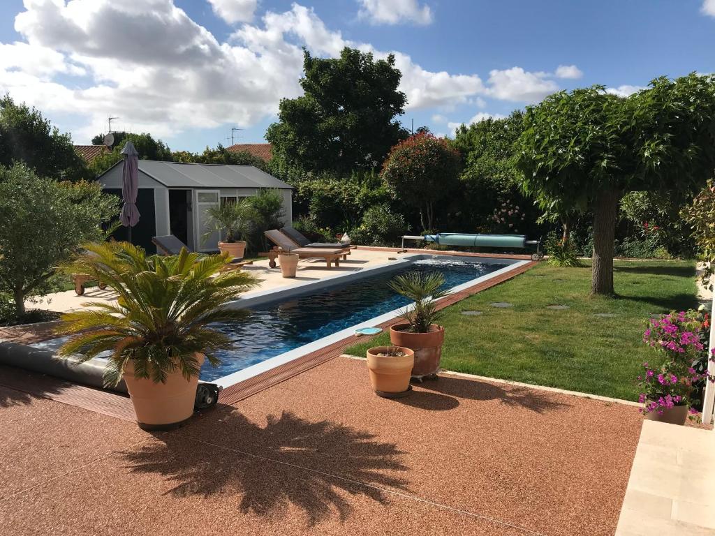 a swimming pool with potted plants in a yard at La Note Bleue - Chambres d'hôtes in Échillais
