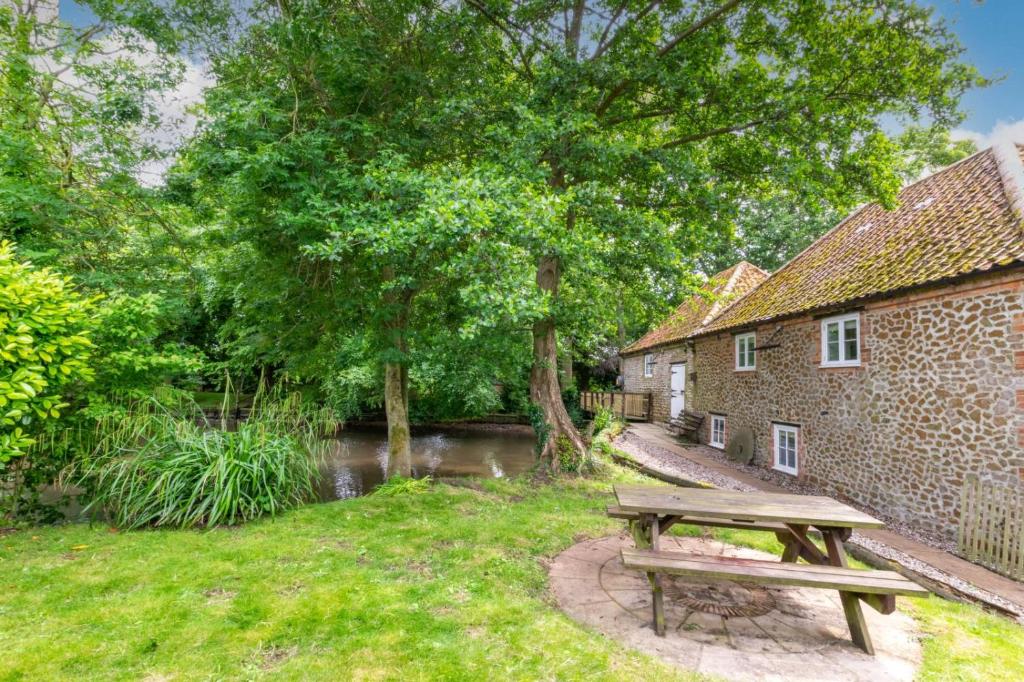 a wooden picnic table in the grass next to a building at Snettisham Watermill Pet Friendly Historic Listed Property in Snettisham