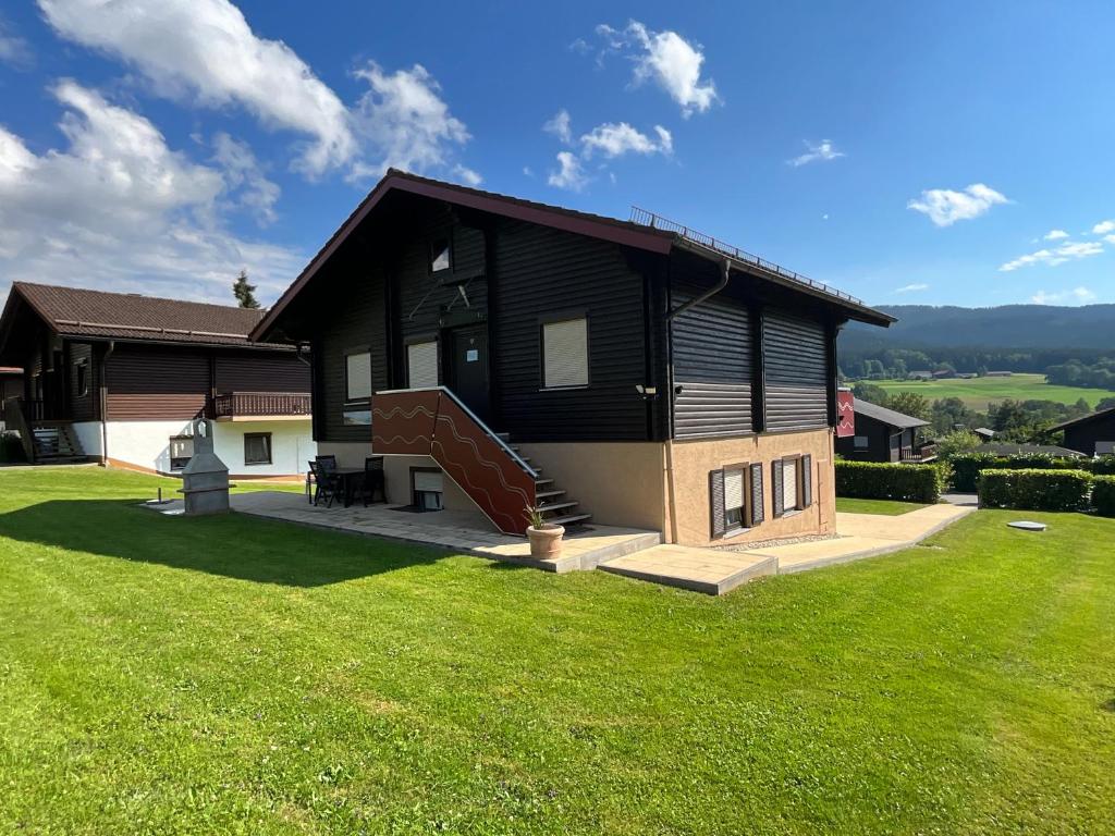 a black house with a grassy yard in front of it at Haus 68 Bergblick in Arrach