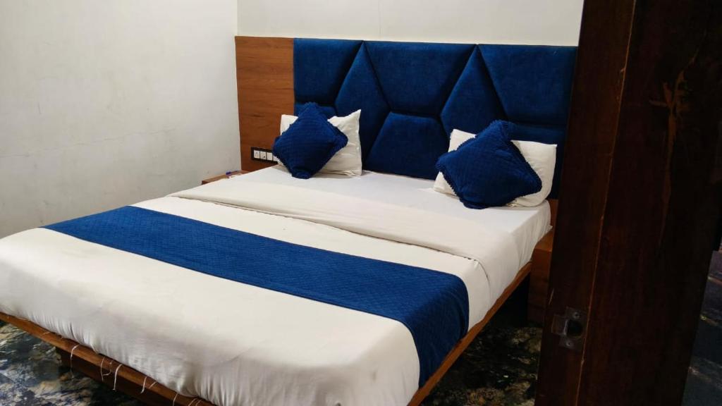 a blue and white bed with blue pillows on it at Hotel New Vinayak in Ahmedabad