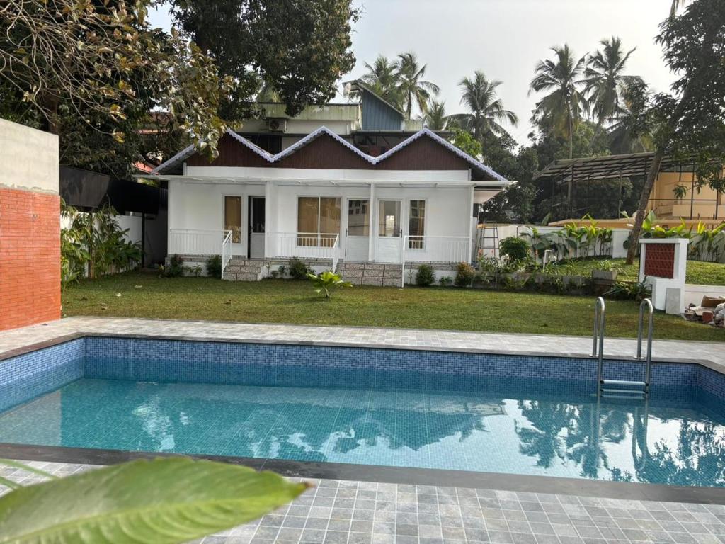 a house with a swimming pool in front of a house at Aagneyam villa in Kozhikode