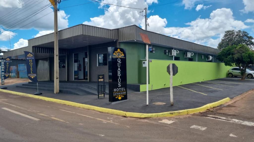 a green building on the corner of a street at Quartus Hotel in Água Boa
