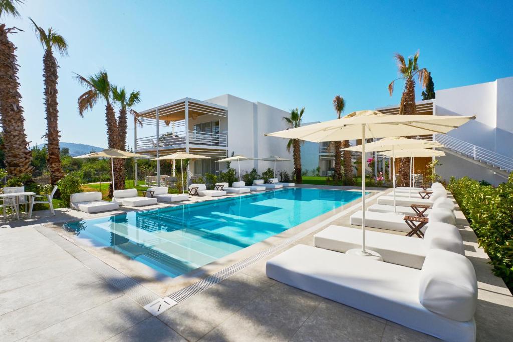 a villa with a swimming pool with chairs and umbrellas at Flamm Residences in Bodrum City