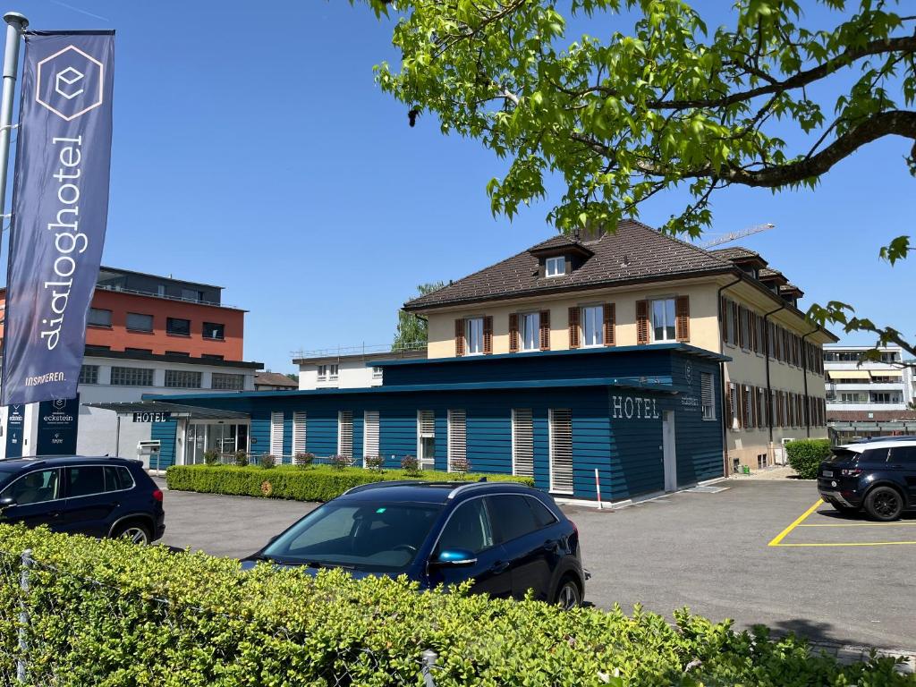 a building with cars parked in a parking lot at Dialoghotel Eckstein in Zug