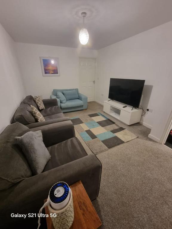 a living room with a couch and a flat screen tv at Beluca homes Acklam in Middlesbrough