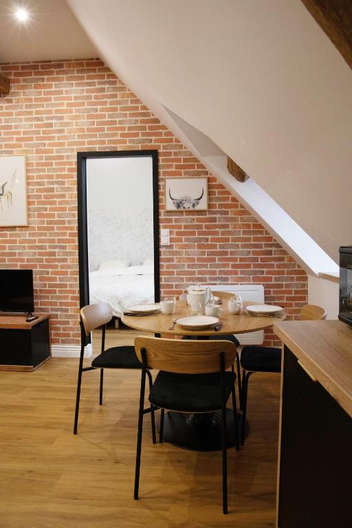 a dining room with a table and chairs and a brick wall at L'auberge du Paon in Troyes