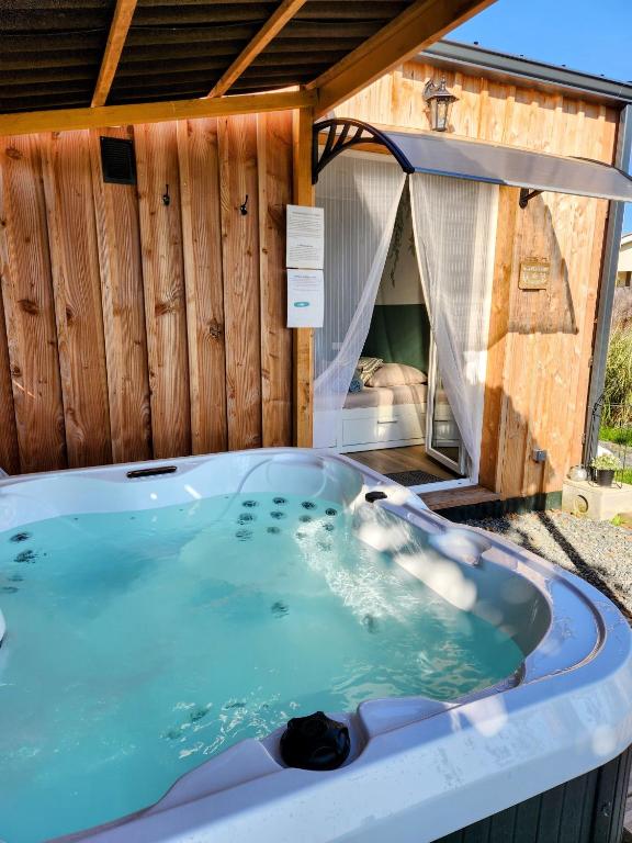 a jacuzzi tub in front of a house at Chalet Cosy avec option Jacuzzi in Saint-Genès-de-Fronsac