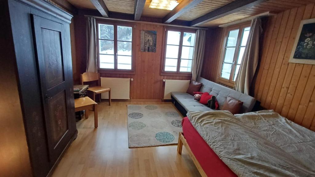 a living room with a couch and a table and windows at Familienzimmer mit Bergblick in Emmetten