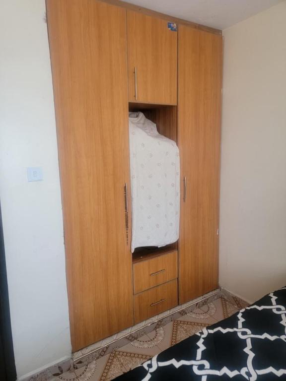 a wooden cabinet in a bedroom with a bed at Owen's Home in Nairobi