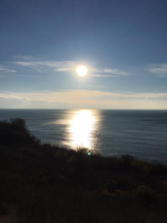 a view of the ocean with the sun in the sky at Seaside Apartment Golf Coast in Topola