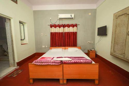 a bed in a room with a red curtain at Hotel Evergreen in Āsansol