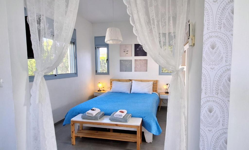 a bedroom with a blue bed and a window at Nof Beresheet suites in Neot Golan