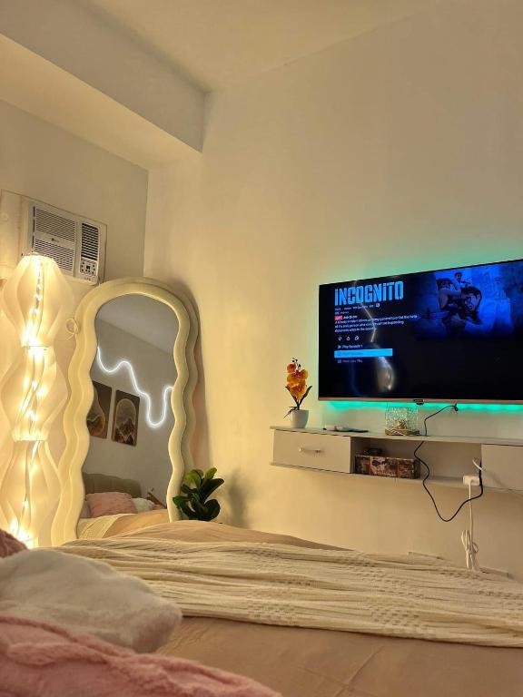 a bedroom with a bed with a tv on the wall at Sweetluxx - SMDC Green 2 Residences Staycation in Dasmariñas