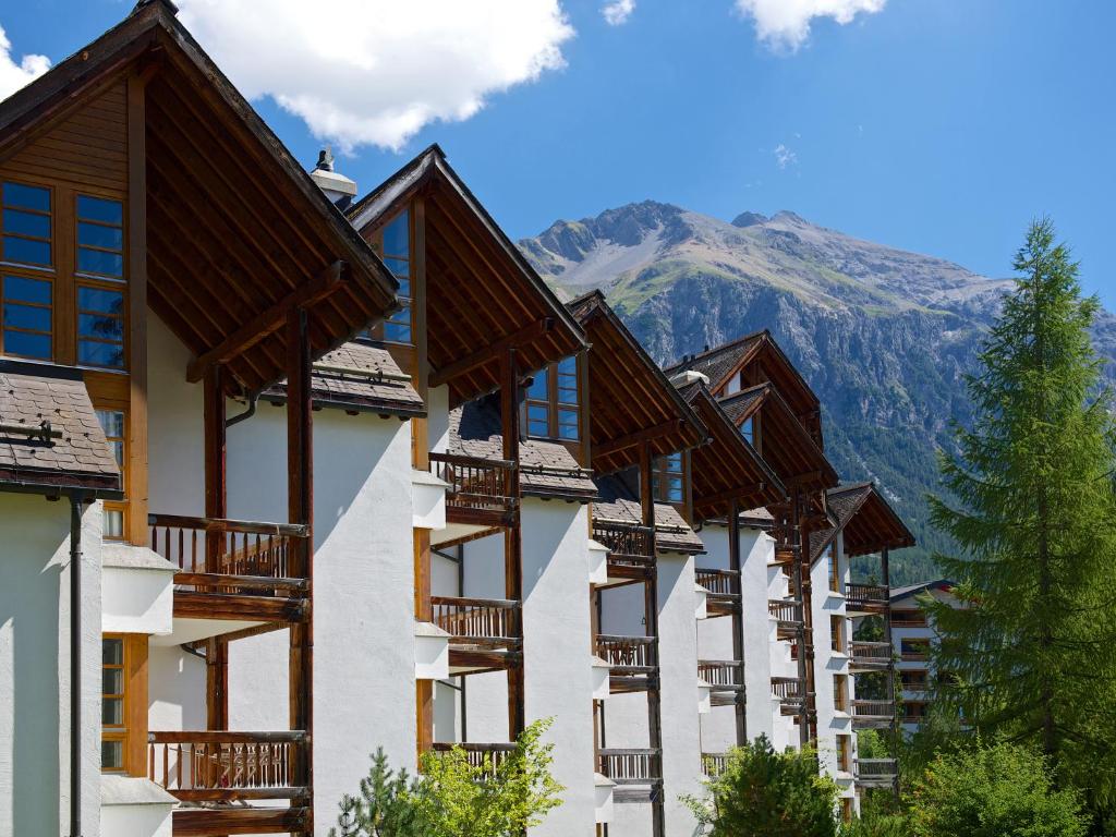 una fila de edificios de apartamentos con montañas en el fondo en Schweizerhof Ferienwohnungen Lenzerheide 5, en Lenzerheide