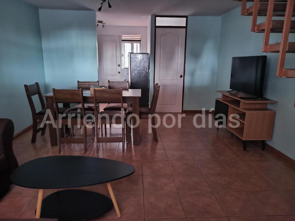 a living room with a table and chairs and a tv at Casa Sierra Nevada in Antofagasta