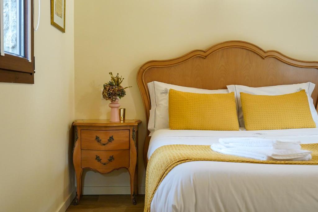a bed with a wooden headboard and a nightstand next to a bed sidx at Casas da Assureira in Castro Laboreiro