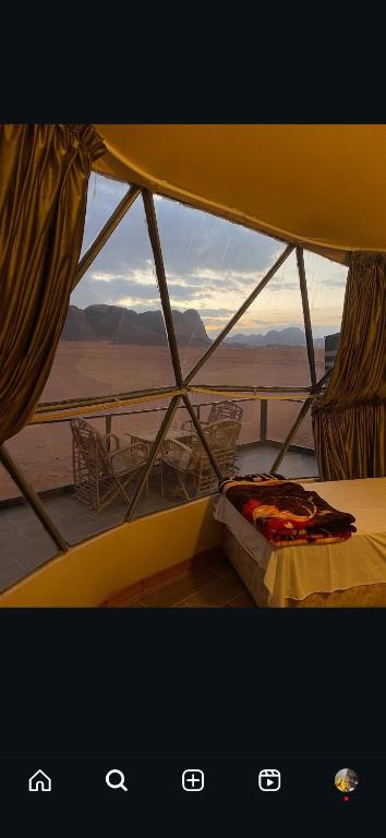a bed in a tent with a view of the desert at Golden Camp- wadi rum in Wadi Rum