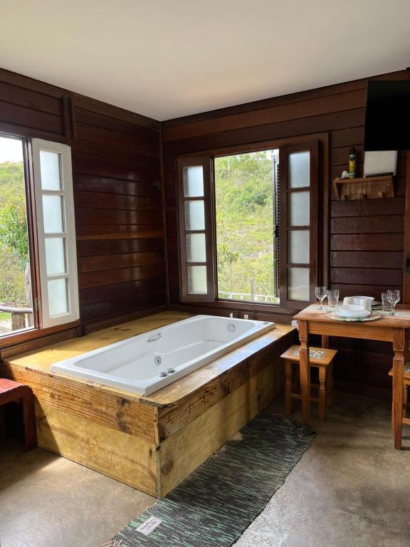 a large bath tub in a room with windows at Chalé Flor da Fortuna in Lavras Novas
