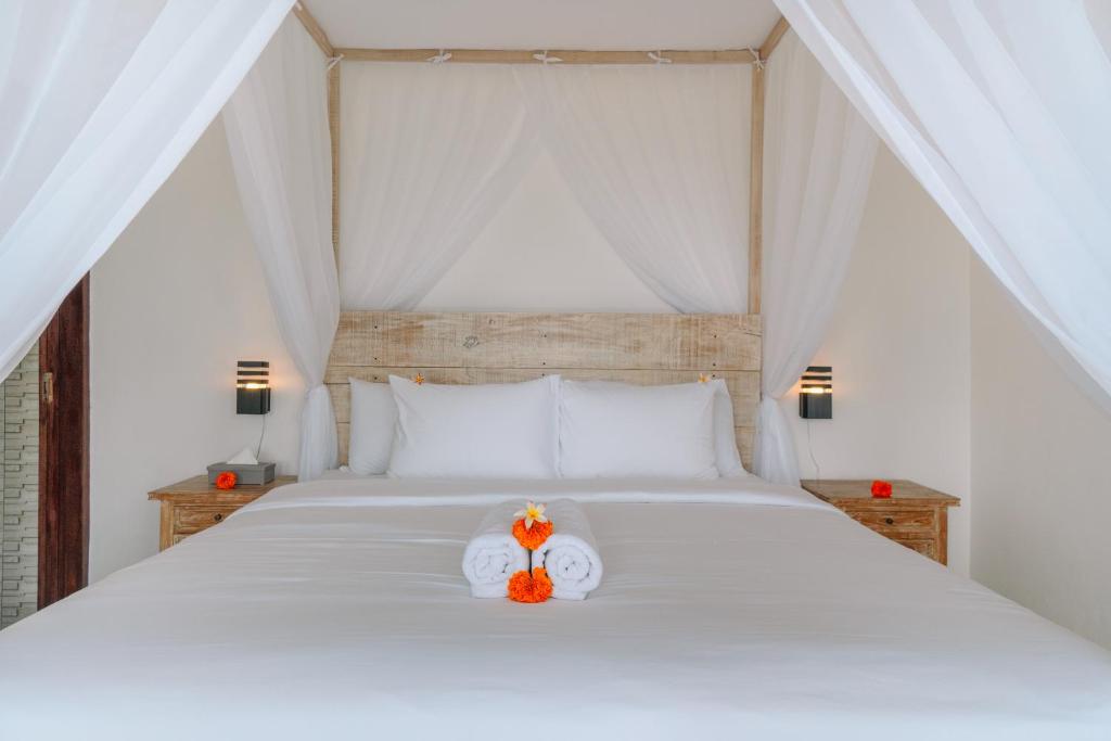a bedroom with a white bed with two orange flowers at Putra House Ubud in Ubud