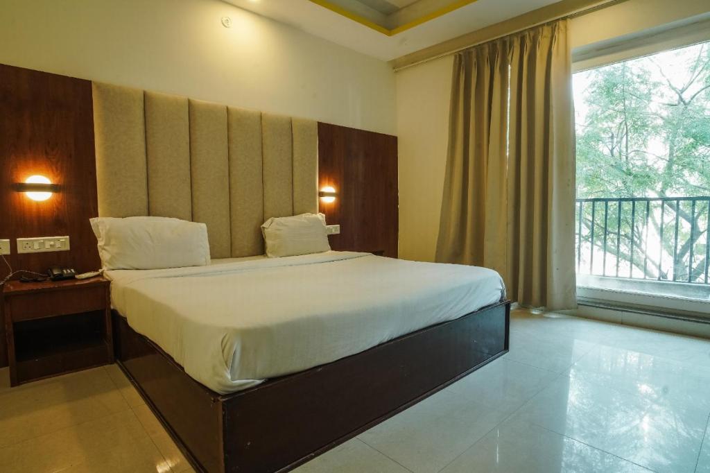 a bedroom with a large bed and a large window at Tapovan Namaste in Rishīkesh