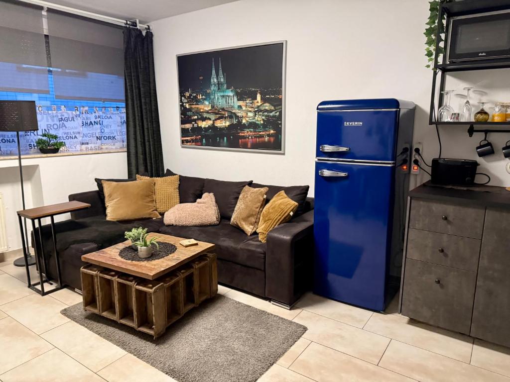 a living room with a couch and a blue refrigerator at Köln Apartment I in Cologne