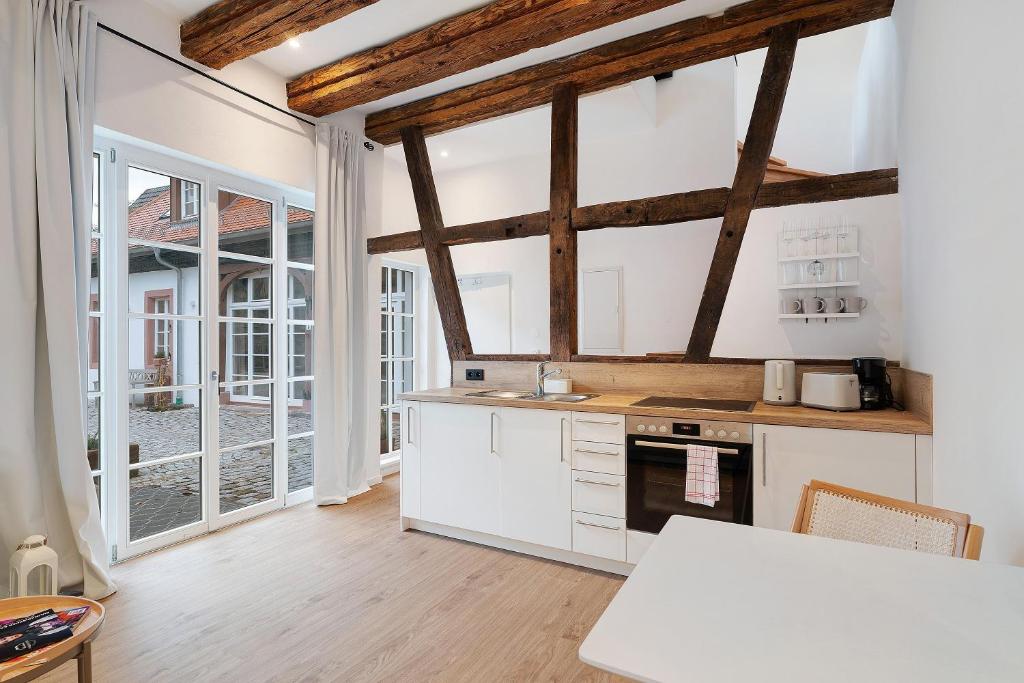 a kitchen with white cabinets and a large window at Historisches Forstamt in Gernsbach