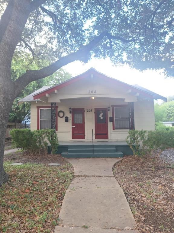 a small white house with red doors and a sidewalk at Cozy Home close to Downtown in San Antonio