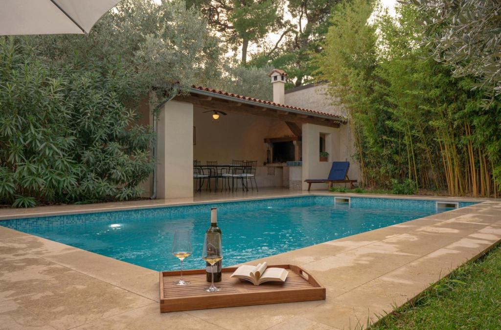 a bottle of wine sitting on a tray next to a swimming pool at Bamboo Garden Oasis with Pool in Pula