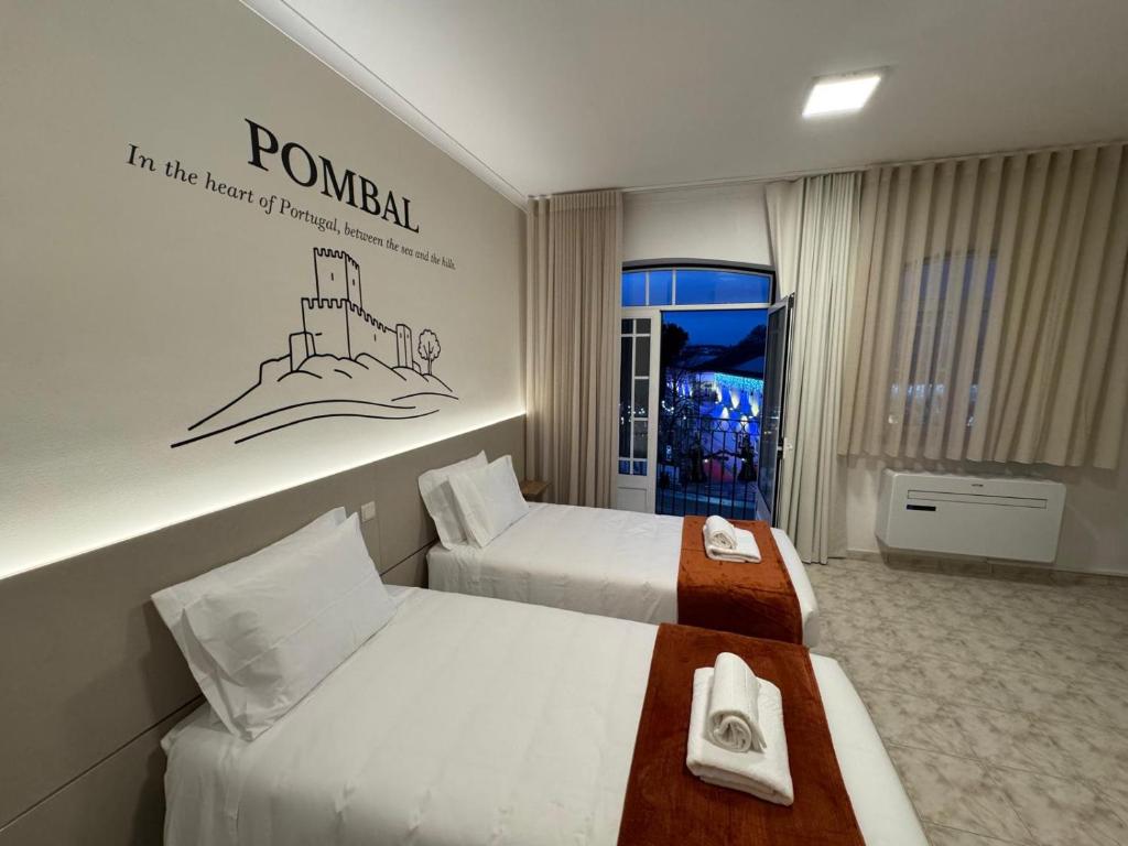 a hotel room with two beds and a sign on the wall at Pombal City House in Pombal