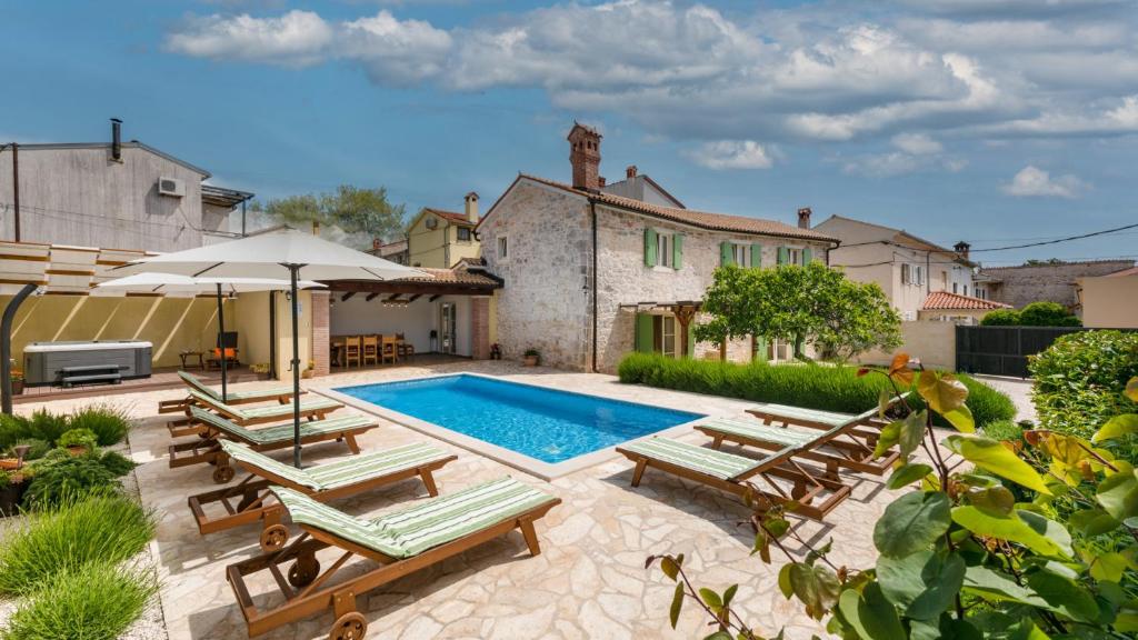 a swimming pool with lounge chairs and an umbrella at Villa Katja by Villas Guide in Peruški