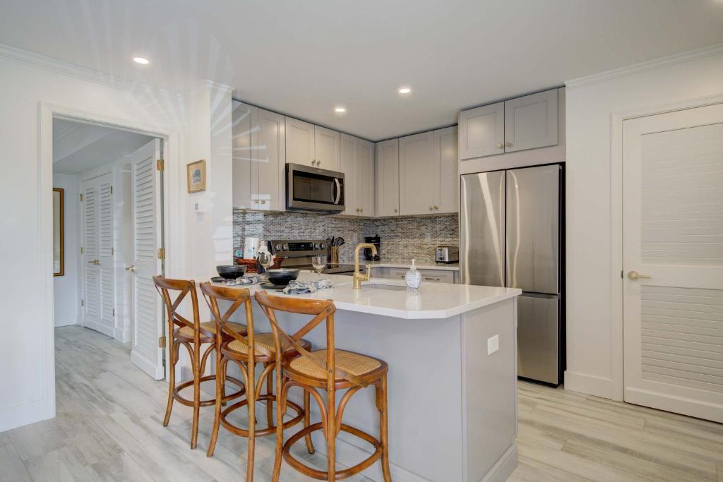 a kitchen with white cabinets and a island with bar stools at Le Malo Vacation Rental in Naples