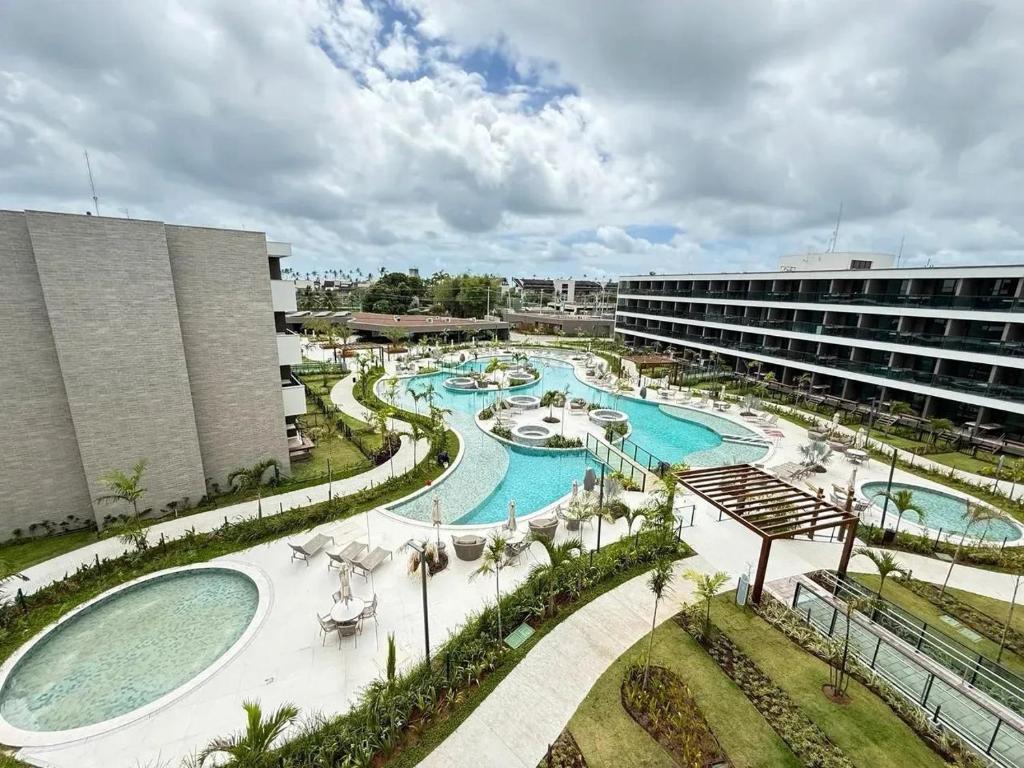 a resort with two pools and a building at Flat Garden 02-A - Beach Class Verano - Porto de Galinhas in Ipojuca