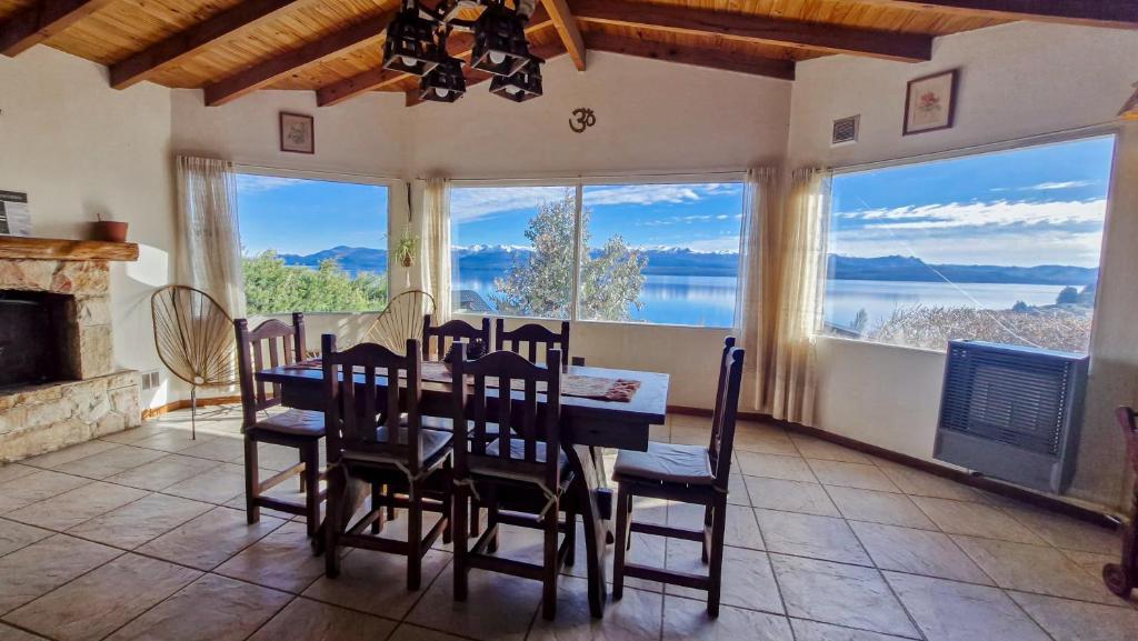 a dining room with a table and chairs and large windows at La gringa 1 in San Carlos de Bariloche