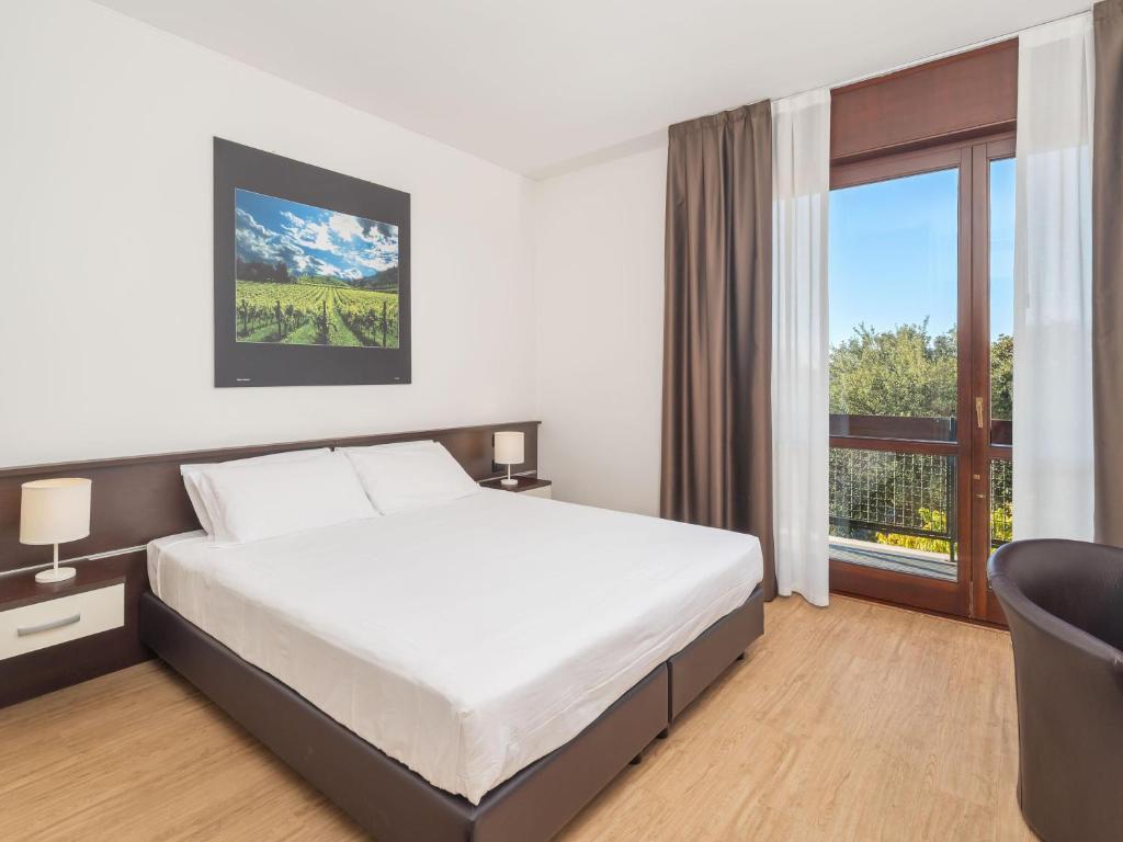 a bedroom with a bed and a large window at B&B HOTEL Eurorest Conegliano in Conegliano