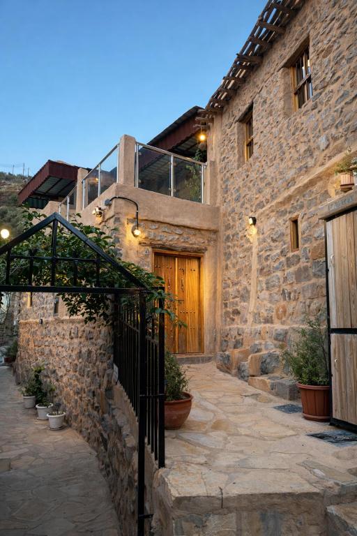 a stone building with a wooden door and a gate at بيت العريش Arish house in Sayq