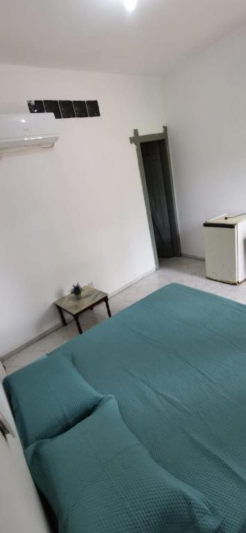 a bed in a room with a green blanket at Verde & Sal 13 in Ilhéus