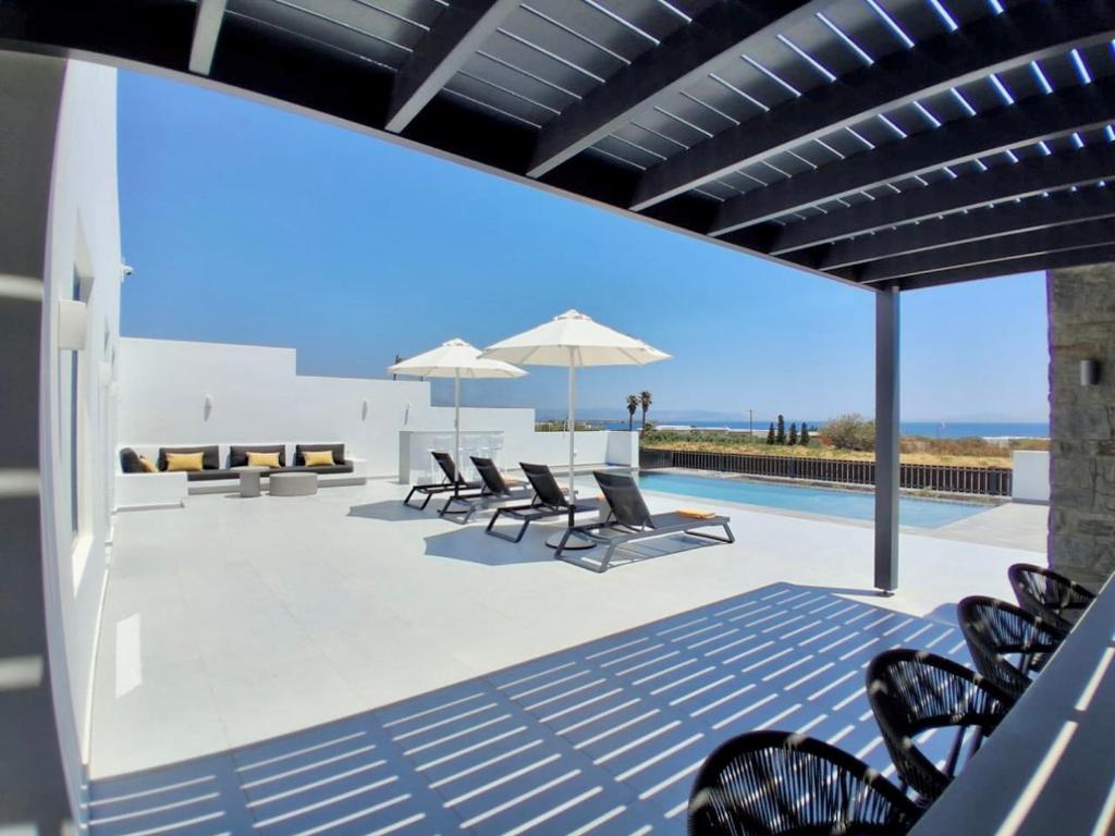 a patio with chairs and umbrellas and a pool at GBR 1 - Golden Beach Residences in Chrissi Akti
