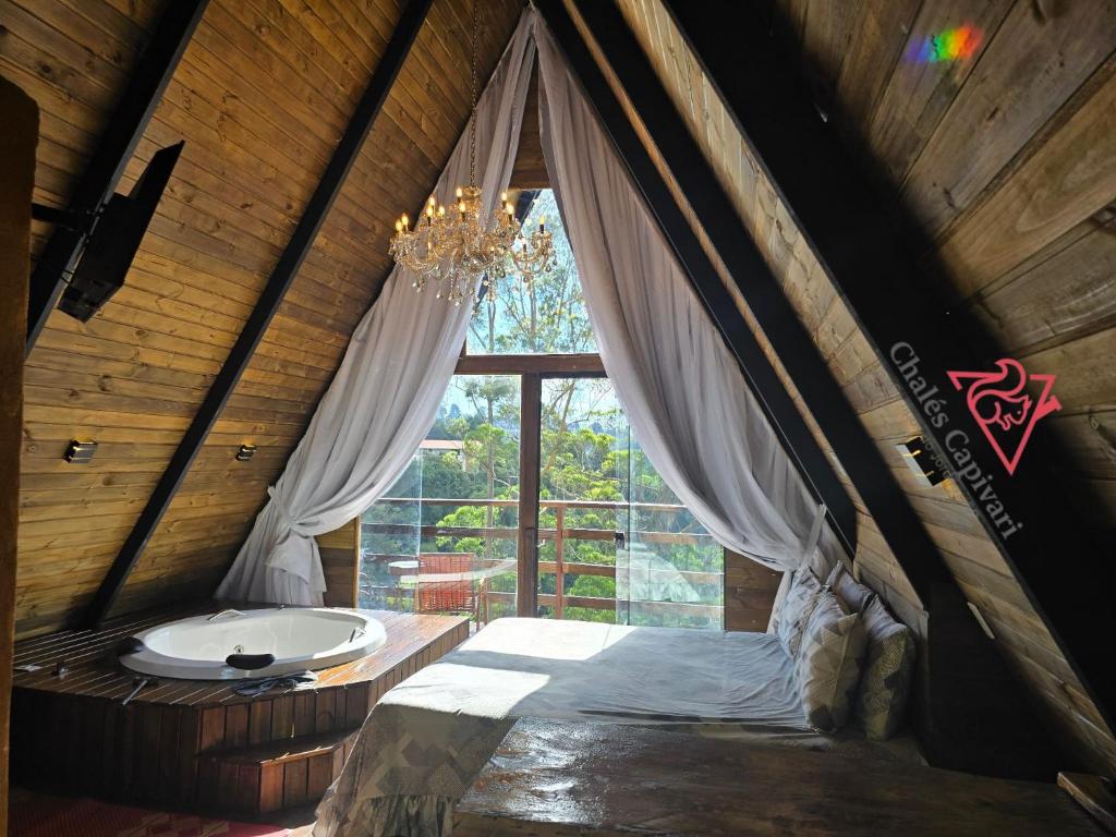 a bedroom with a bed with a chandelier and a window at Chale Capivari Estrela in Campos do Jordão