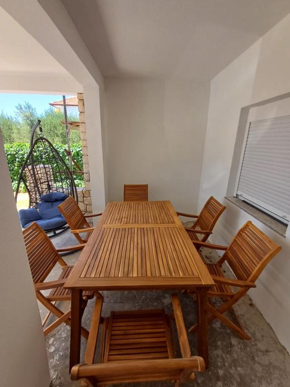 a wooden table and chairs in a room with a window at Apartman Danijel in Bibinje