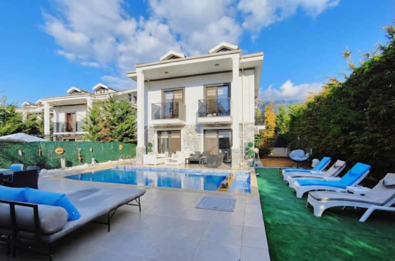 a house with a swimming pool and some chairs at Serenity Hideaway Hisarönü in Fethiye