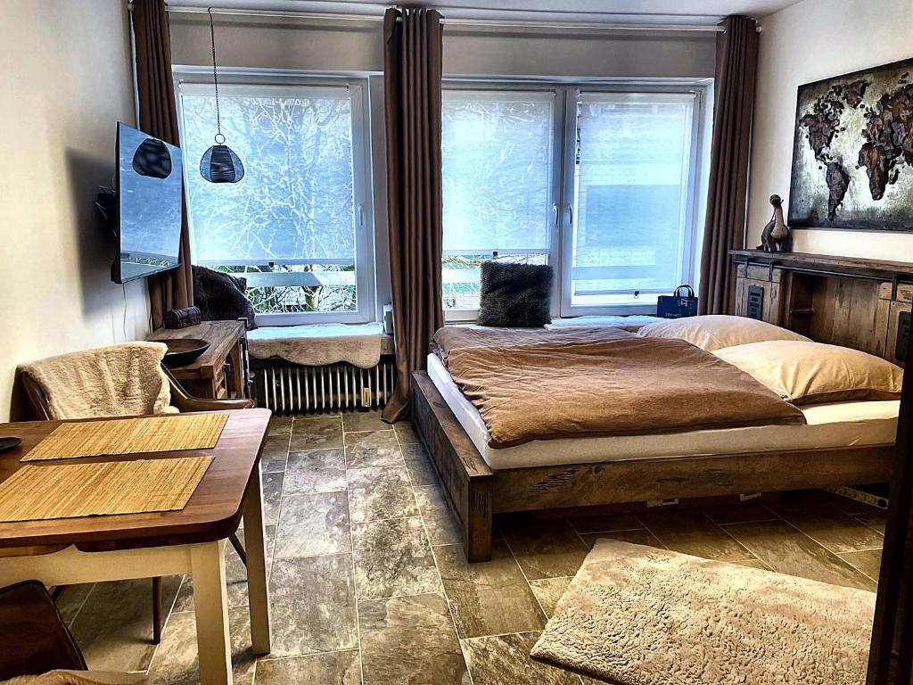 a bedroom with a bed and a table and two windows at City Apartment in Cologne
