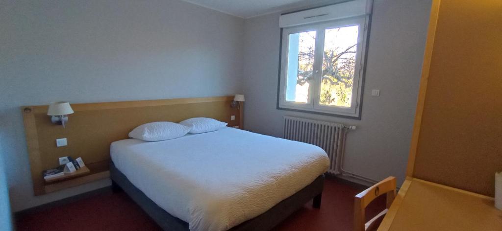 a bedroom with a white bed and a window at Logis Hotel Restaurant Le Cygne in Yssingeaux