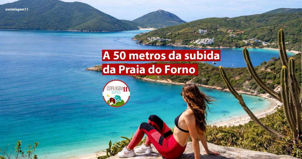 a woman sitting on a cliff overlooking a beach at Estalagem 11 Suites in Arraial do Cabo