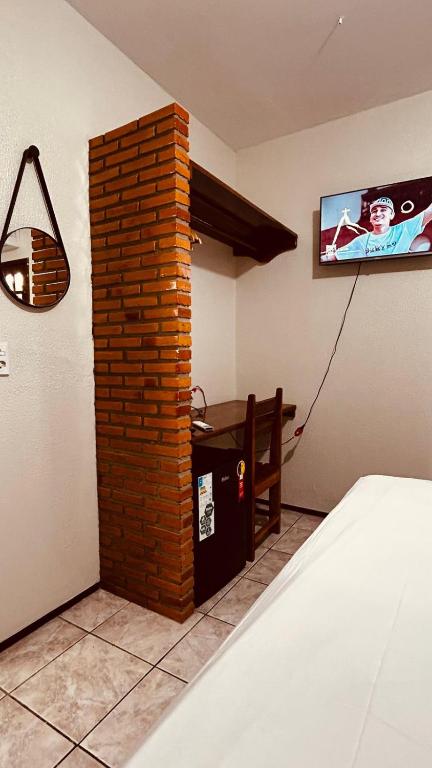 a room with a brick wall and a tv on the wall at Rochas - Suíte no Centro de Viçosa do Ceará in Viçosa do Ceará