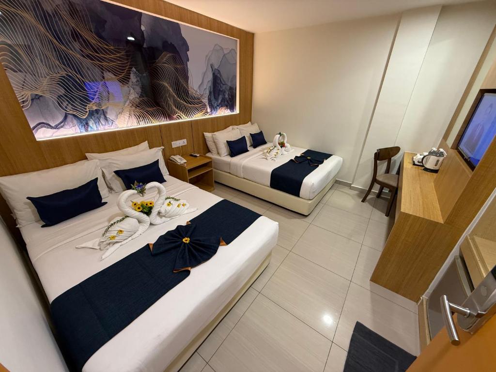 A two-bed room with a desk, tea station, television, artwork and a mirrored wall.