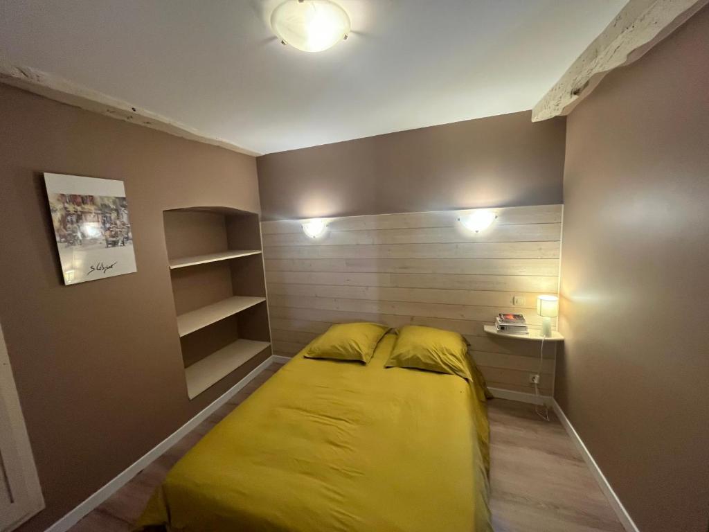 a small bedroom with a yellow bed and shelves at Apartment in Mostuejouls in Mostuéjouls